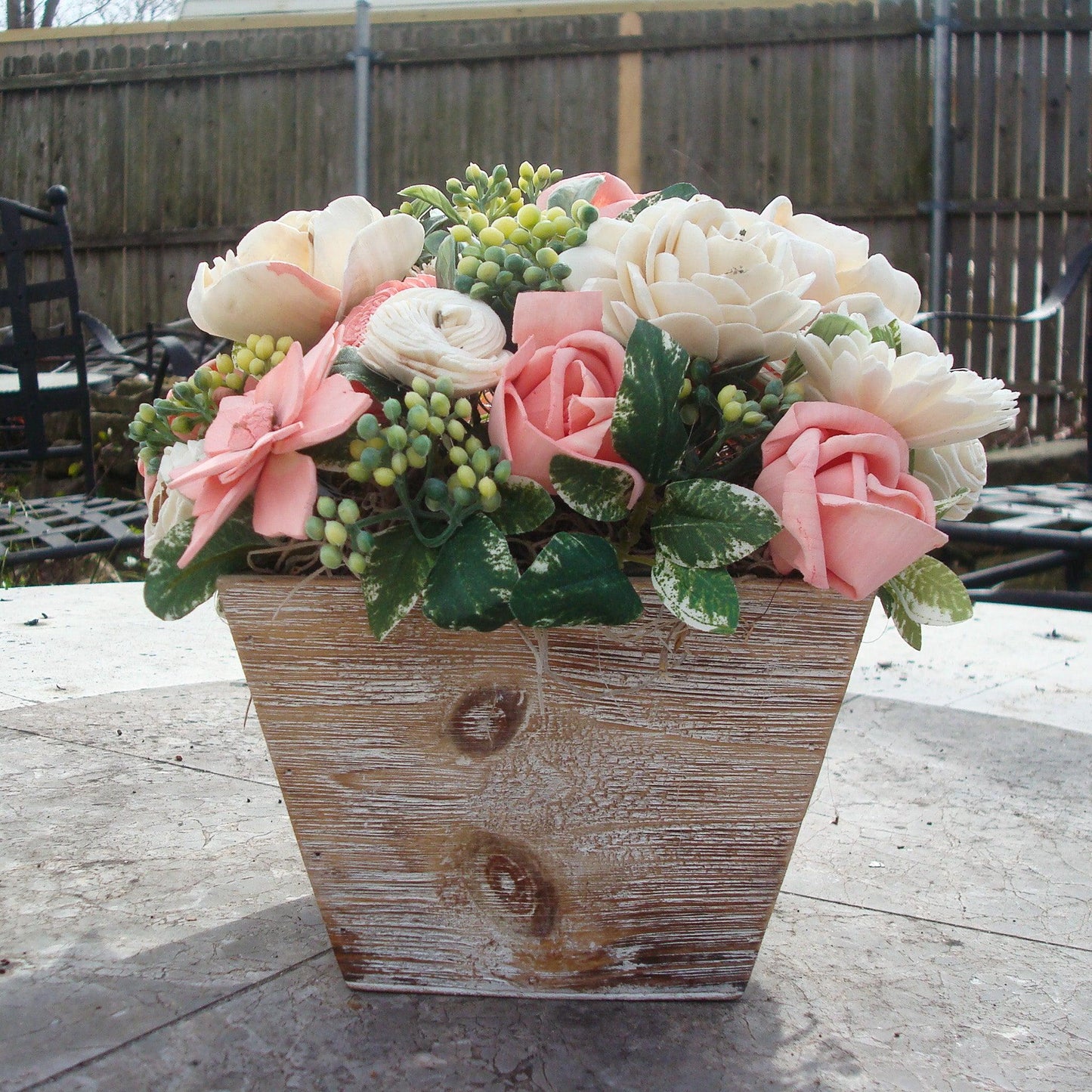 Pale pink in white Sola flowers in a washed wood planter