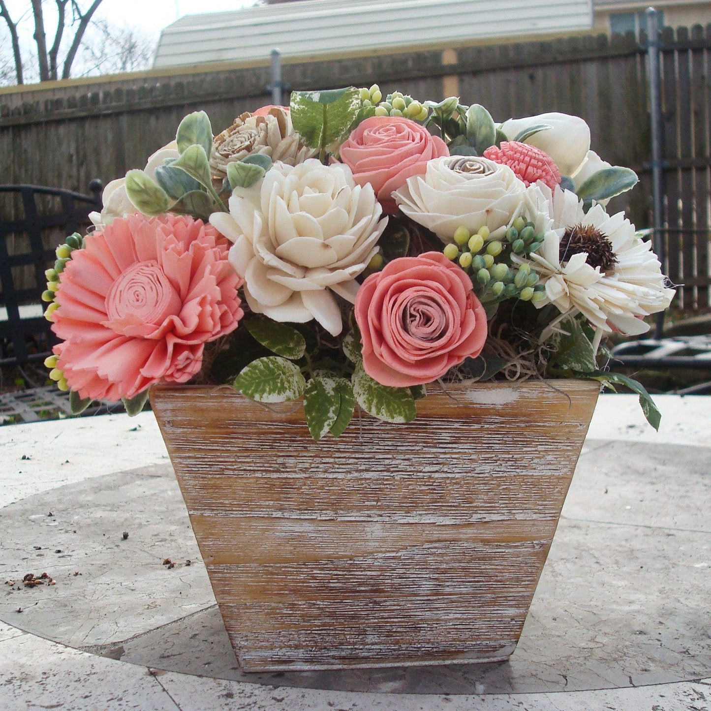 Pale pink in white Sola flowers in a washed wood planter